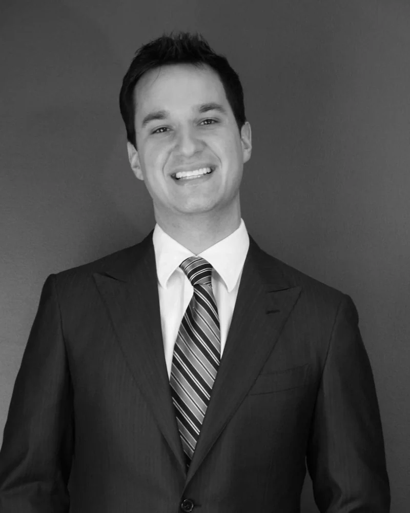 Dr. Danny Domingue, in a dark suit and striped tie, black and white portrait.
