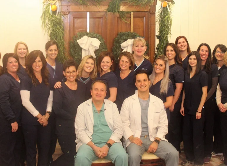 The whole team of Drs. Smith and Domingue in navy scrubs, with Dr. Smith and Dr. Domingue seated at the front in white coats.